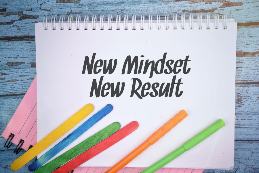 A notepad with the word "New Mindset New Result" with colored pens.