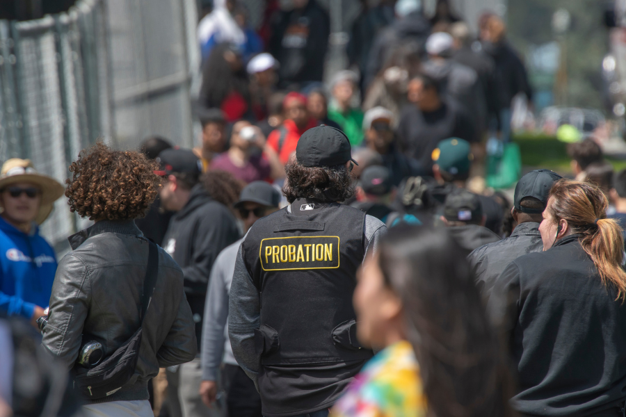 A probation officer walking through a large crowd, turned away from the camera.