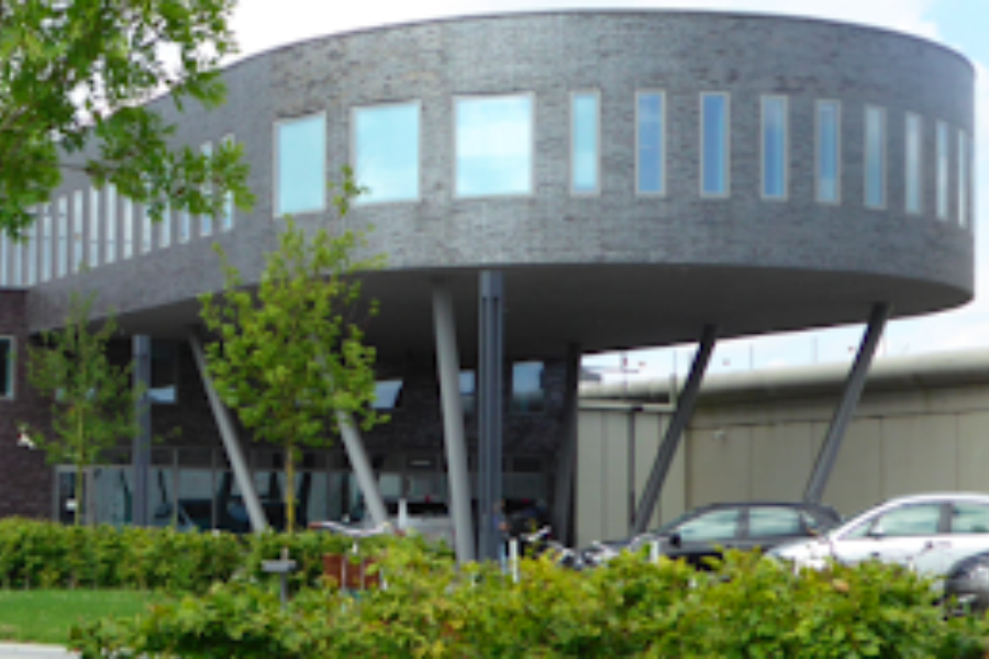 Photograph of FPC Ghent facility exterior with three cars in the parking lot.