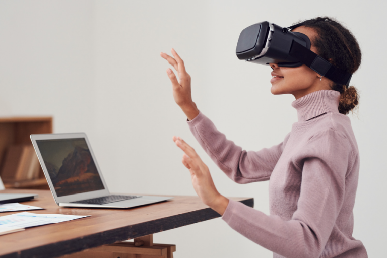 A woman sitting at a desk with a virtual reality mask on.