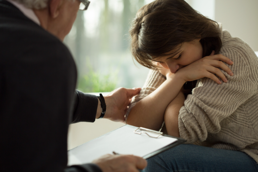 A young woman visibly upset, and a figure extending a hand to comfort her.