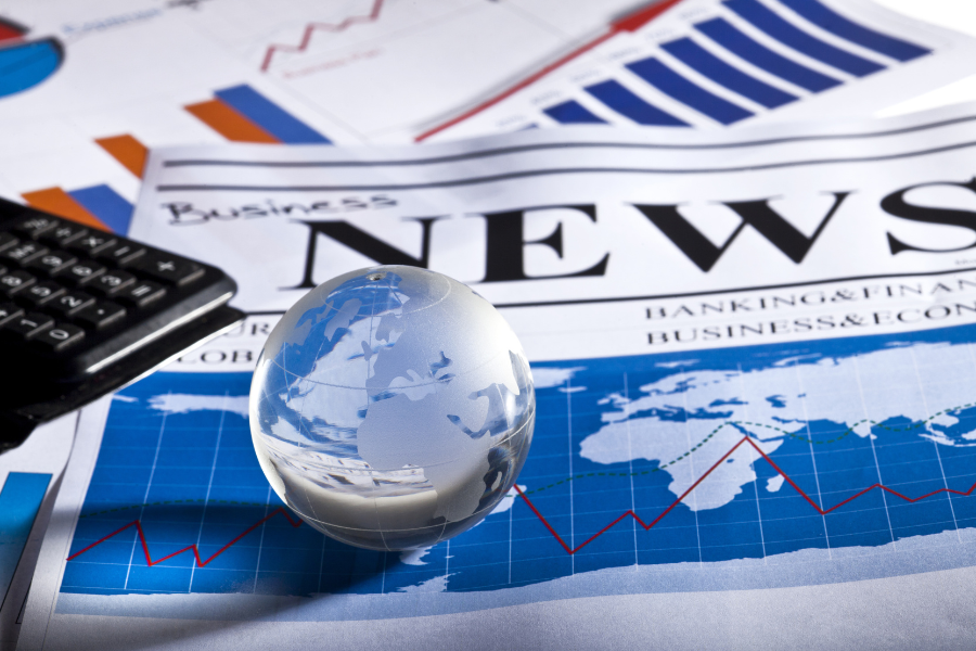 A small metal globe on a stack of newspapers